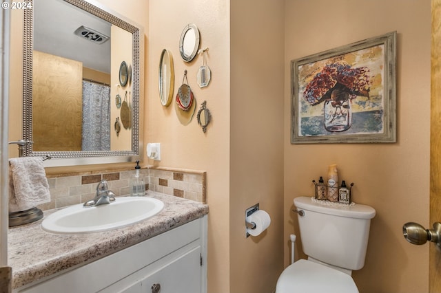 bathroom featuring decorative backsplash, vanity, and toilet