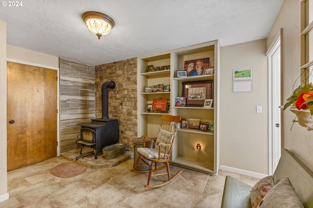 sitting room featuring a wood stove, a textured ceiling, and built in shelves