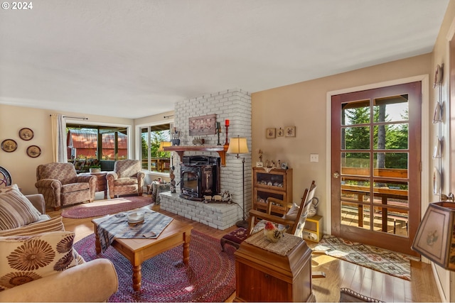 living room featuring light hardwood / wood-style floors, a fireplace, a wood stove, and plenty of natural light