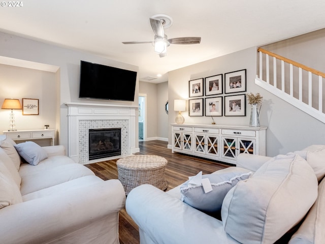 living room featuring a tile fireplace, ceiling fan, and dark wood-type flooring