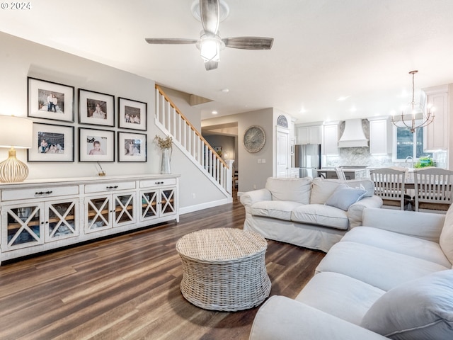 living room featuring ceiling fan with notable chandelier and dark hardwood / wood-style flooring