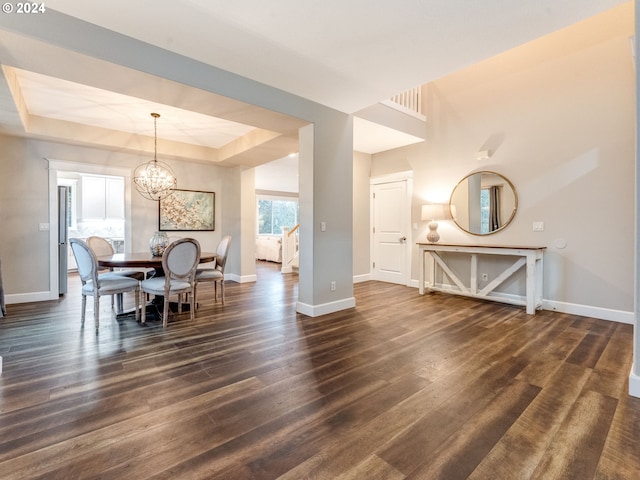 dining area featuring a tray ceiling, dark hardwood / wood-style flooring, and an inviting chandelier