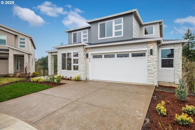 prairie-style home featuring a garage, stone siding, and driveway