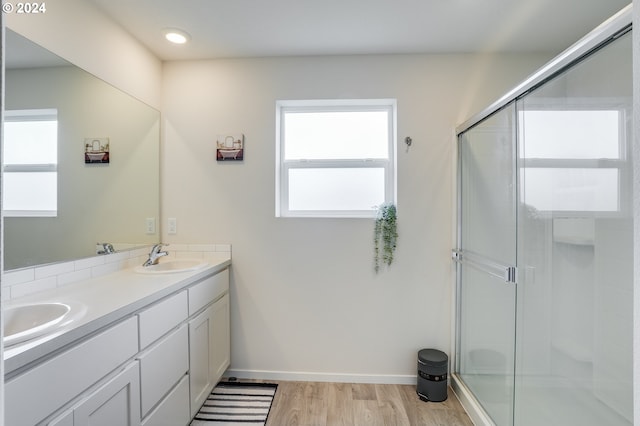 bathroom with a shower with shower door, hardwood / wood-style flooring, and double sink vanity