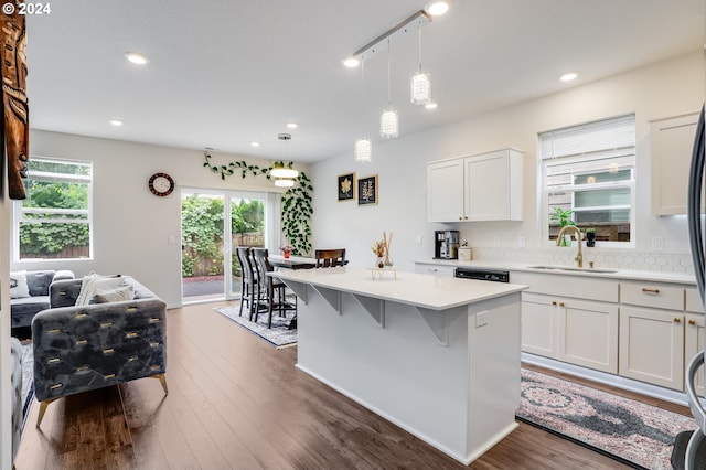 kitchen featuring white cabinetry, decorative light fixtures, sink, a kitchen island, and dark wood-type flooring