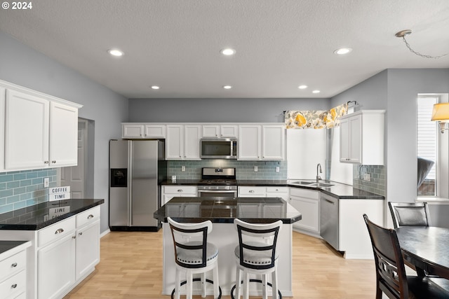 kitchen with white cabinetry, appliances with stainless steel finishes, a kitchen island, and sink