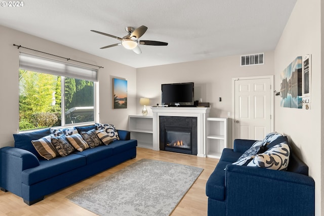 living room with ceiling fan, a textured ceiling, and wood-type flooring