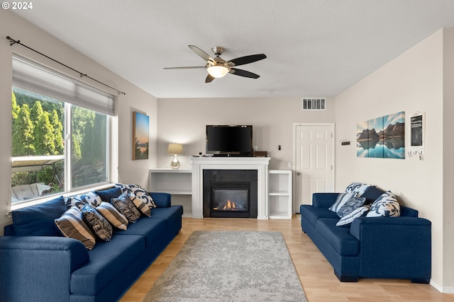 living room featuring a textured ceiling, hardwood / wood-style floors, and ceiling fan