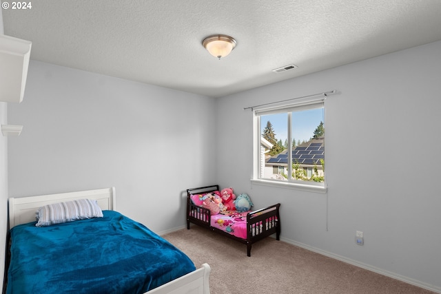 bedroom featuring a textured ceiling and light carpet