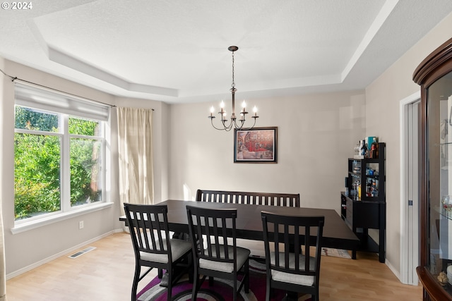 dining room featuring light hardwood / wood-style floors, a tray ceiling, and a chandelier