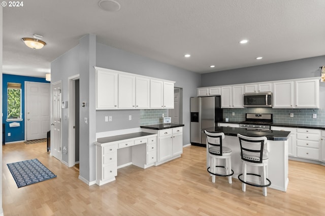 kitchen featuring appliances with stainless steel finishes, white cabinetry, a kitchen island, and light hardwood / wood-style flooring