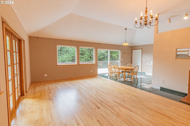 unfurnished dining area with a textured ceiling, lofted ceiling, hardwood / wood-style floors, and a chandelier