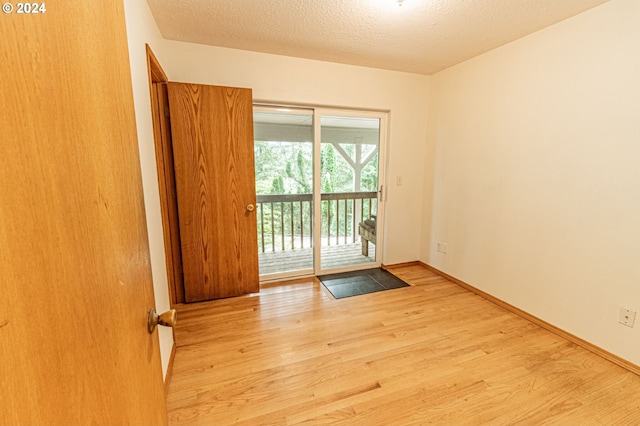 spare room with light wood-type flooring and a textured ceiling