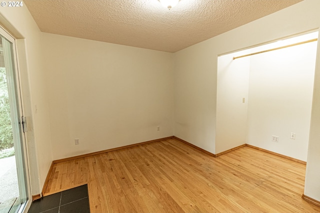 spare room with a textured ceiling and wood-type flooring