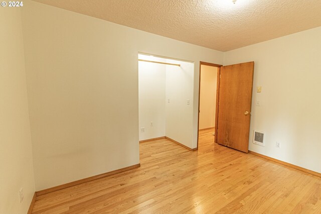 unfurnished bedroom featuring a textured ceiling and light hardwood / wood-style floors