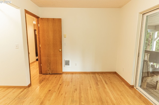 unfurnished room featuring light hardwood / wood-style floors and a textured ceiling