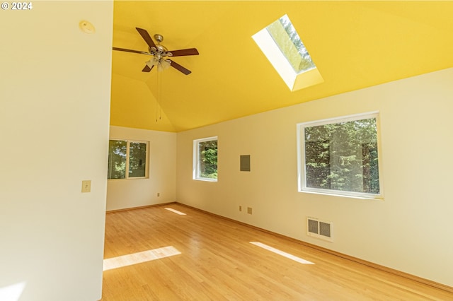 empty room featuring ceiling fan, a skylight, hardwood / wood-style floors, and high vaulted ceiling