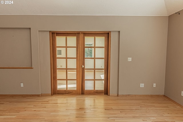 spare room featuring light wood-type flooring, a textured ceiling, and french doors