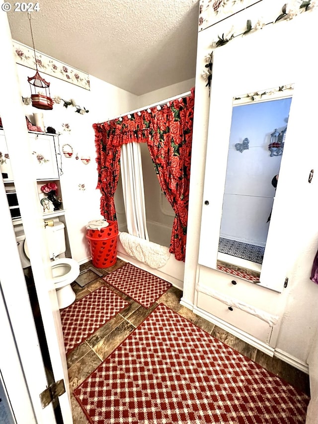 bathroom with tile floors, toilet, and a textured ceiling