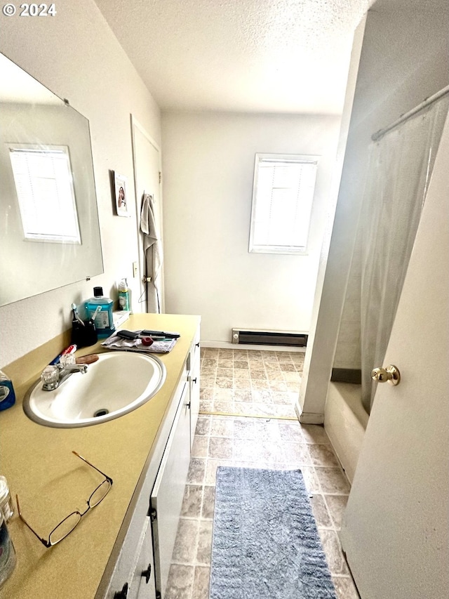 bathroom with a healthy amount of sunlight, tile flooring, a textured ceiling, and vanity