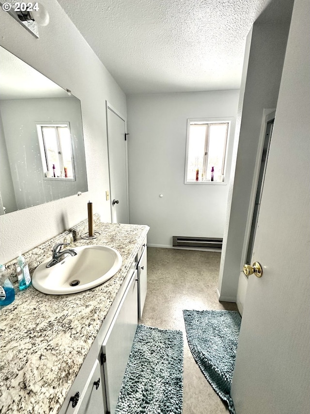 bathroom featuring baseboard heating, a textured ceiling, and large vanity