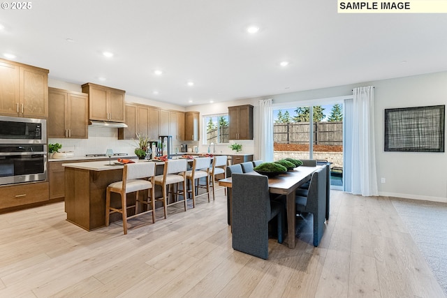 kitchen with a center island, a kitchen bar, stainless steel appliances, and light hardwood / wood-style flooring