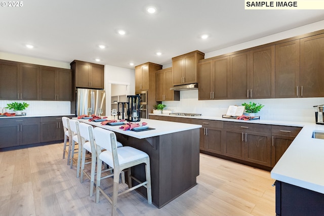 kitchen featuring a kitchen breakfast bar, a center island, stainless steel appliances, and light hardwood / wood-style flooring