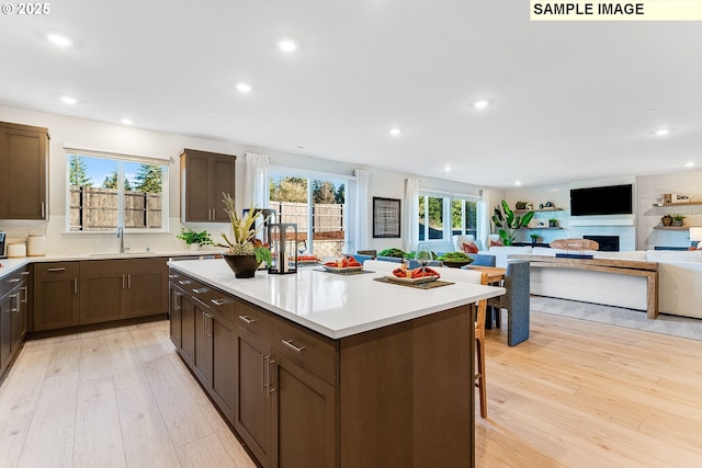 kitchen with a kitchen bar, light wood-type flooring, a kitchen island, and sink