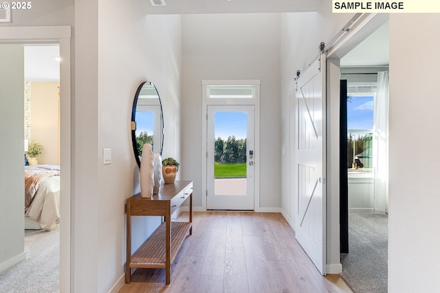 entrance foyer with a barn door, light hardwood / wood-style floors, and a wealth of natural light