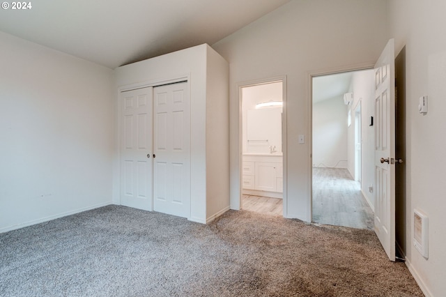 unfurnished bedroom featuring a closet, carpet floors, and lofted ceiling