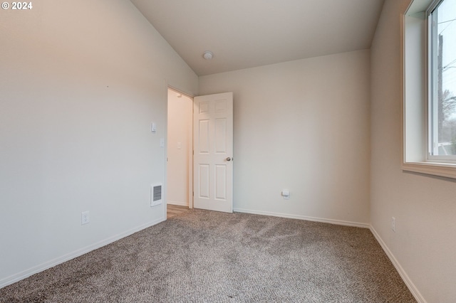 carpeted empty room with vaulted ceiling