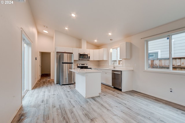 kitchen with high vaulted ceiling, light hardwood / wood-style floors, a kitchen island, white cabinetry, and stainless steel appliances