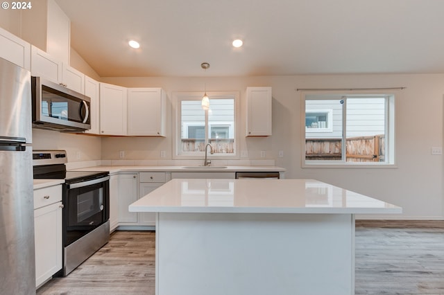 kitchen featuring white cabinets, hanging light fixtures, and appliances with stainless steel finishes