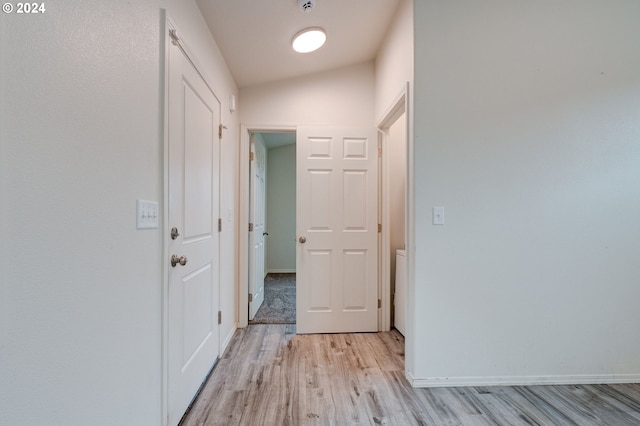 hallway with light hardwood / wood-style floors and lofted ceiling