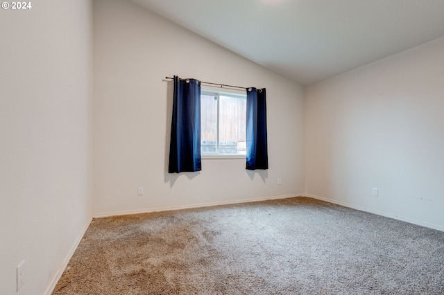 carpeted empty room with vaulted ceiling