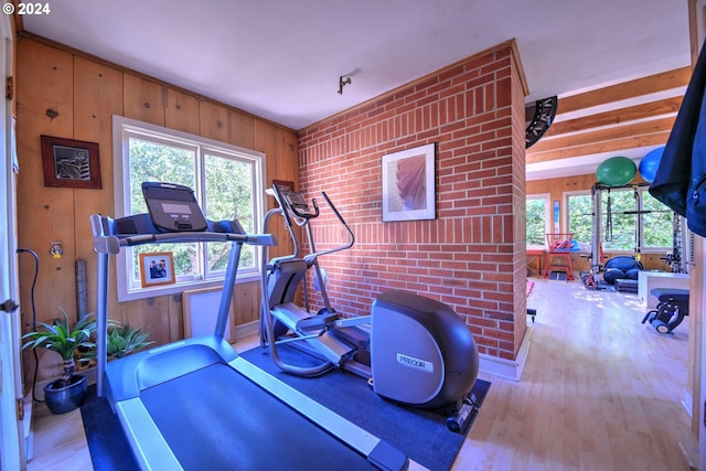 workout room with brick wall and light wood-type flooring