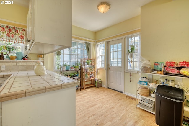 kitchen featuring tile countertops, kitchen peninsula, and light hardwood / wood-style flooring