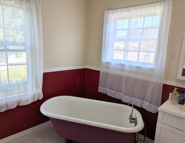 bathroom with a bath, tile patterned flooring, a wealth of natural light, and vanity