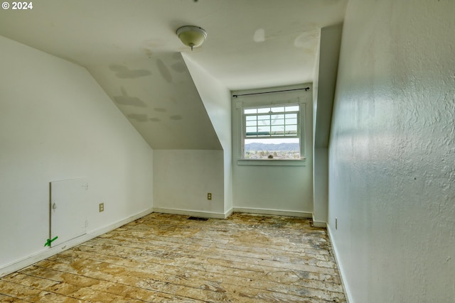 additional living space featuring light hardwood / wood-style floors and vaulted ceiling