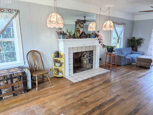 living room featuring a fireplace, wood-type flooring, and ceiling fan