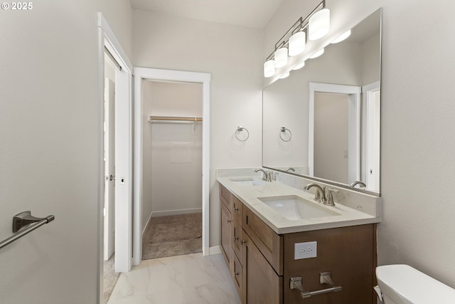 full bath with marble finish floor, a spacious closet, double vanity, and a sink