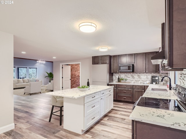 kitchen featuring appliances with stainless steel finishes, light wood-type flooring, backsplash, sink, and white cabinets