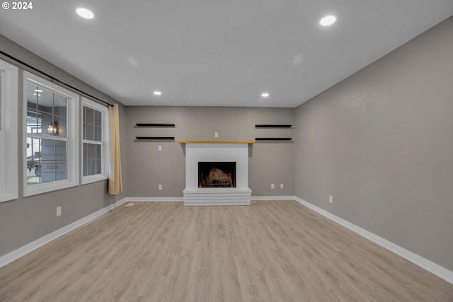 unfurnished living room with a fireplace and light hardwood / wood-style floors