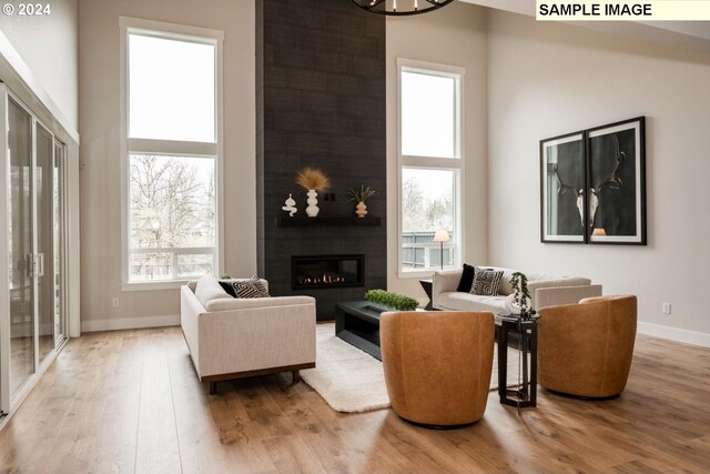 living room featuring hardwood / wood-style flooring, a fireplace, and a high ceiling