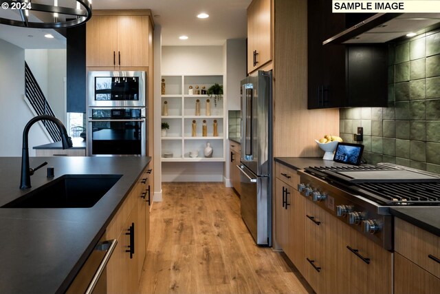 kitchen with sink, backsplash, exhaust hood, stainless steel appliances, and light hardwood / wood-style floors