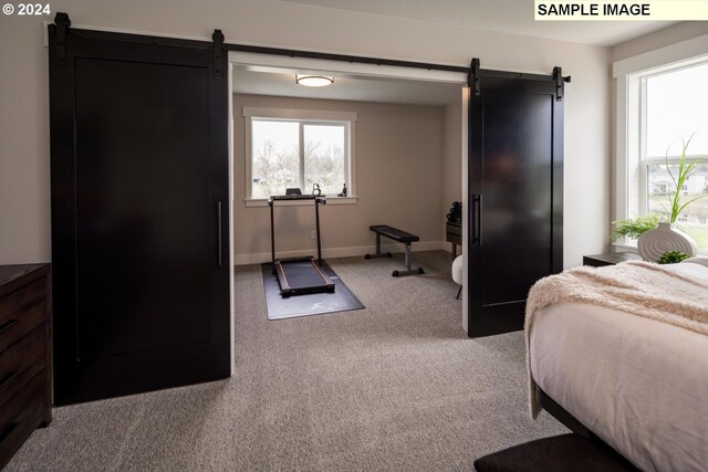 bedroom featuring a barn door and light colored carpet