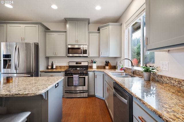 kitchen with a kitchen breakfast bar, light wood-type flooring, sink, gray cabinets, and stainless steel appliances