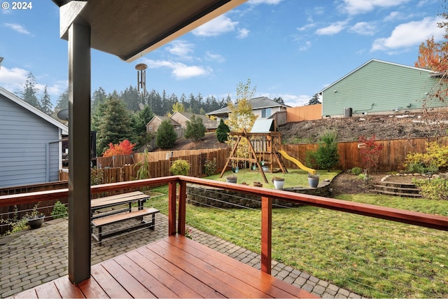 wooden terrace featuring a lawn and a playground