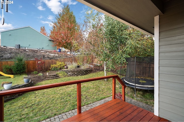 wooden terrace featuring a lawn and a trampoline