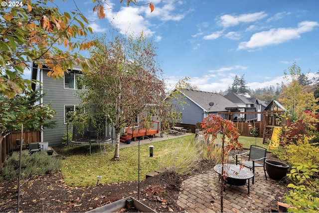 view of yard featuring a patio area, a playground, and a trampoline